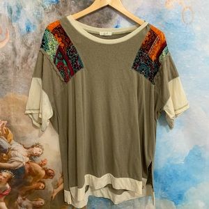 Army green top with floral patches and embroidery.